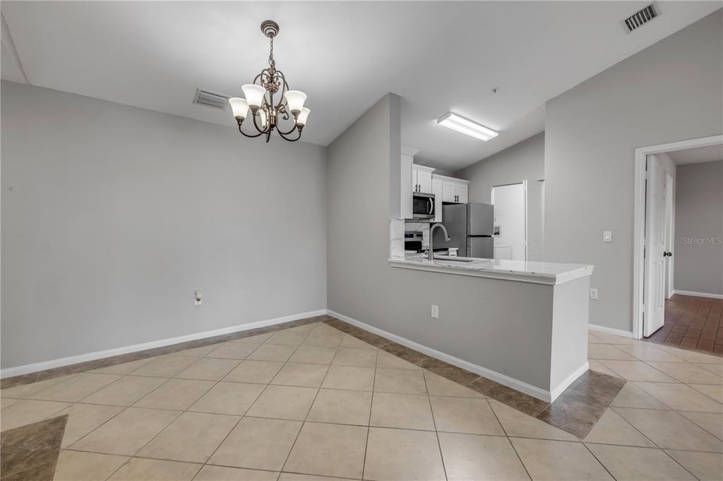 A dining area with a chandelier sits adjacent to a kitchen with a breakfast bar — 940 VILLAGE TRAIL UNIT 4-306, PORT ORANGE, FL
