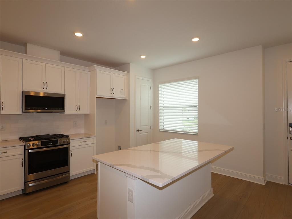 A modern kitchen features white cabinetry, stainless steel appliances, and a central quartz island — 4458 SUNSET GARDEN STREET, BRADENTON, FL