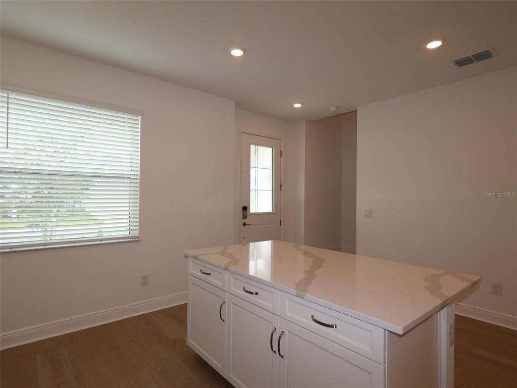 A kitchen island with white cabinets and a quartz countertop sits in a room — 4458 SUNSET GARDEN STREET, BRADENTON, FL