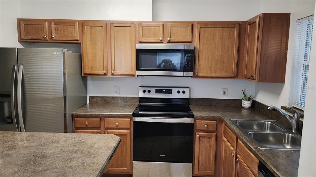A kitchen features wood cabinets, stainless steel appliances, and dark laminate countertops — 5436 E MICHIGAN STREET UNIT 5436-3, ORLANDO, FL