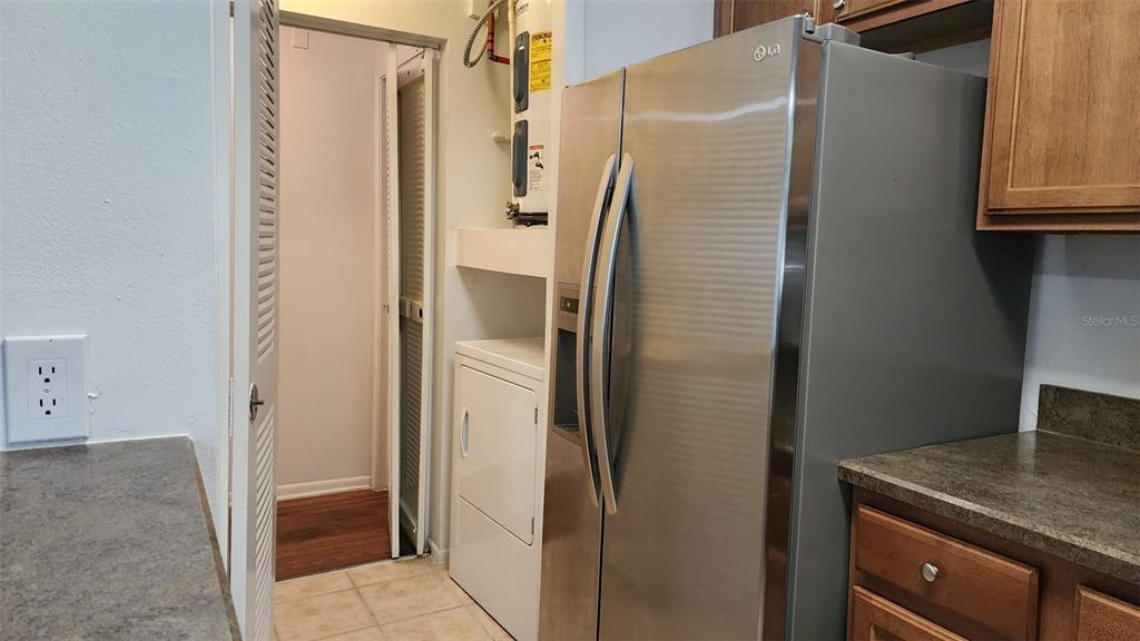 A kitchen features a stainless steel refrigerator, a white dryer, and a water heater — 5436 E MICHIGAN STREET UNIT 5436-3, ORLANDO, FL