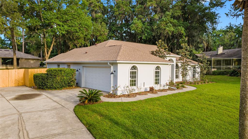 A white single-story house with a two-car garage, arched windows, and a concrete driveway — 4857 NW 83RD TERRACE, OCALA, FL