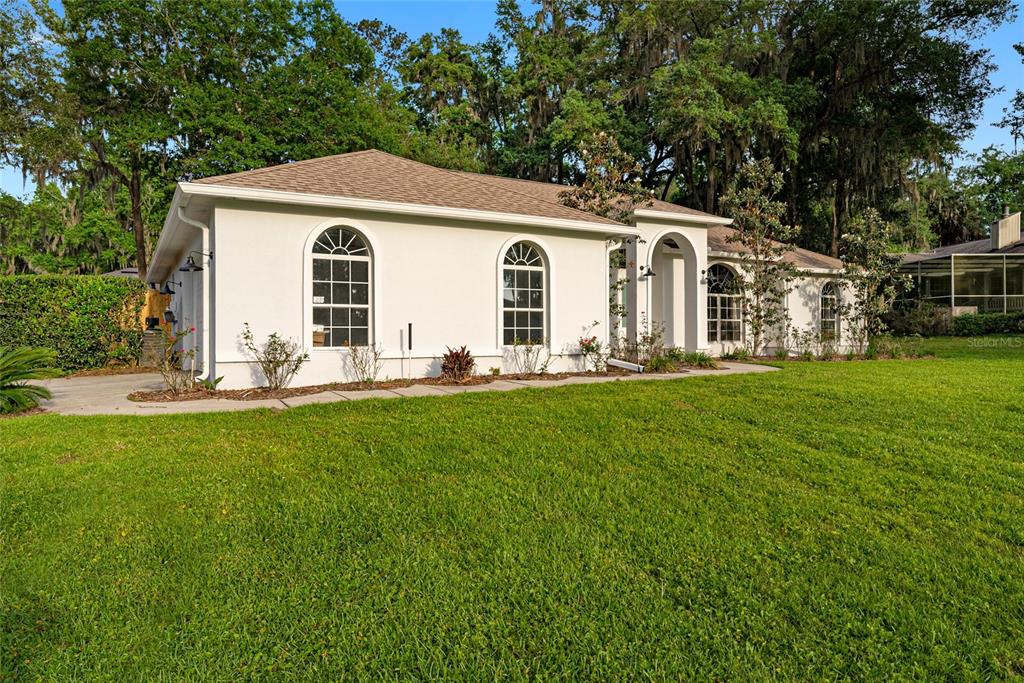 A single-story white house with arched windows and a covered entryway sits on a lawn — 4857 NW 83RD TERRACE, OCALA, FL
