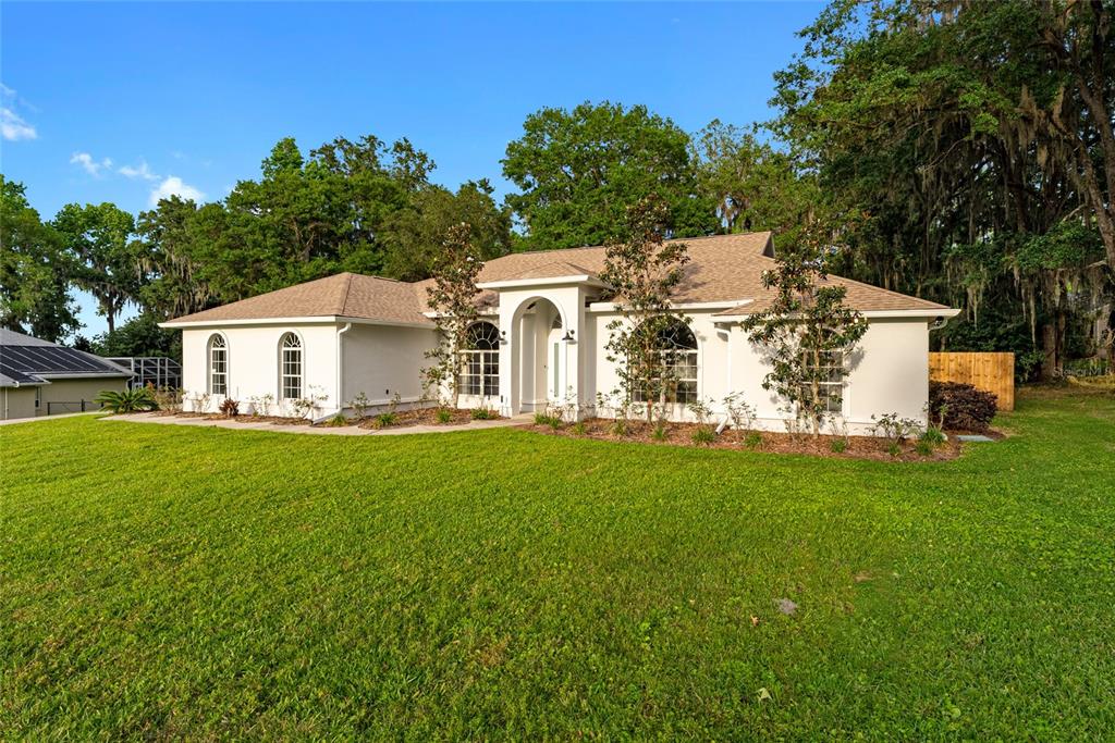 A white single-story house with a hip roof sits on a large green lawn — 4857 NW 83RD TERRACE, OCALA, FL