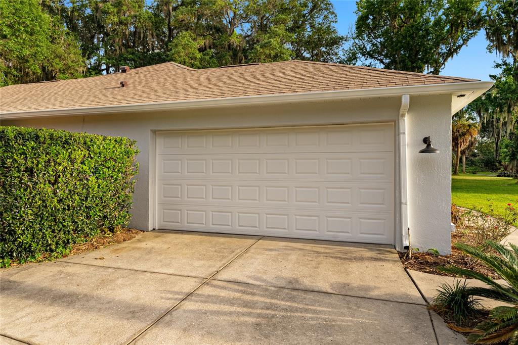 A white garage door is set into a stucco wall with a concrete driveway outside — 4857 NW 83RD TERRACE, OCALA, FL