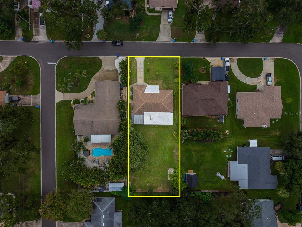 An aerial view shows a single-story house with a large backyard outlined in yellow — 3042 KAPOK KOVE DRIVE, CLEARWATER, FL