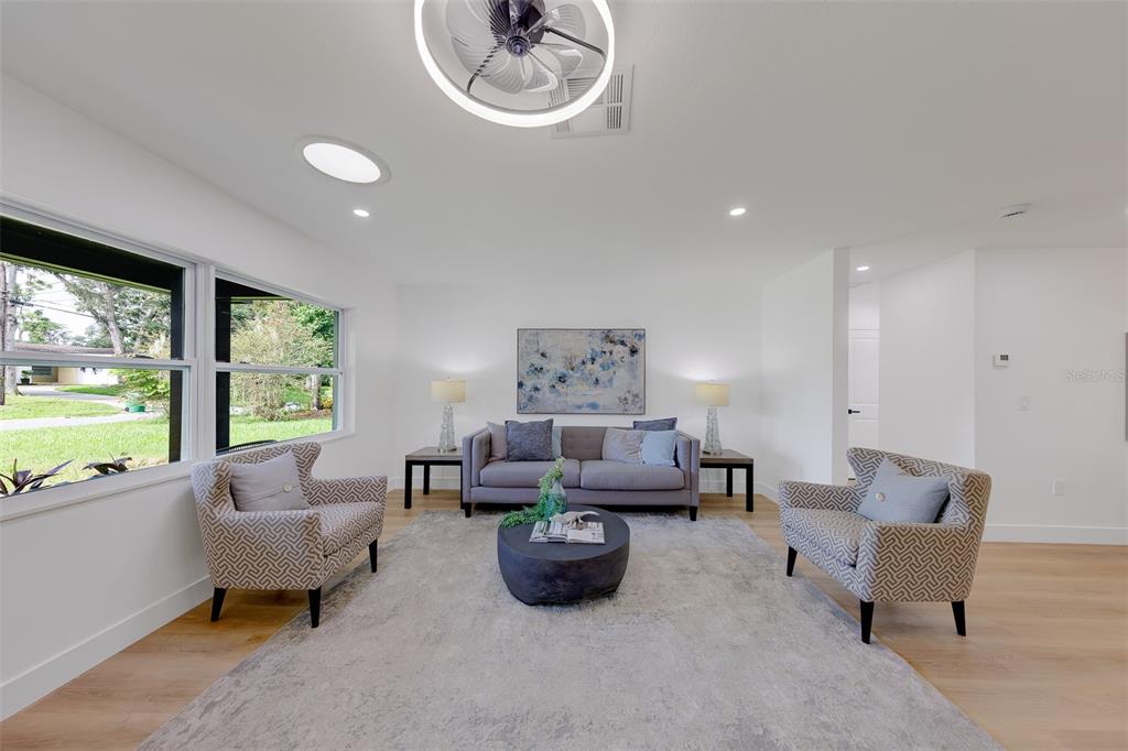 A living room features a gray sofa, two patterned armchairs, and a circular coffee table — 3042 KAPOK KOVE DRIVE, CLEARWATER, FL