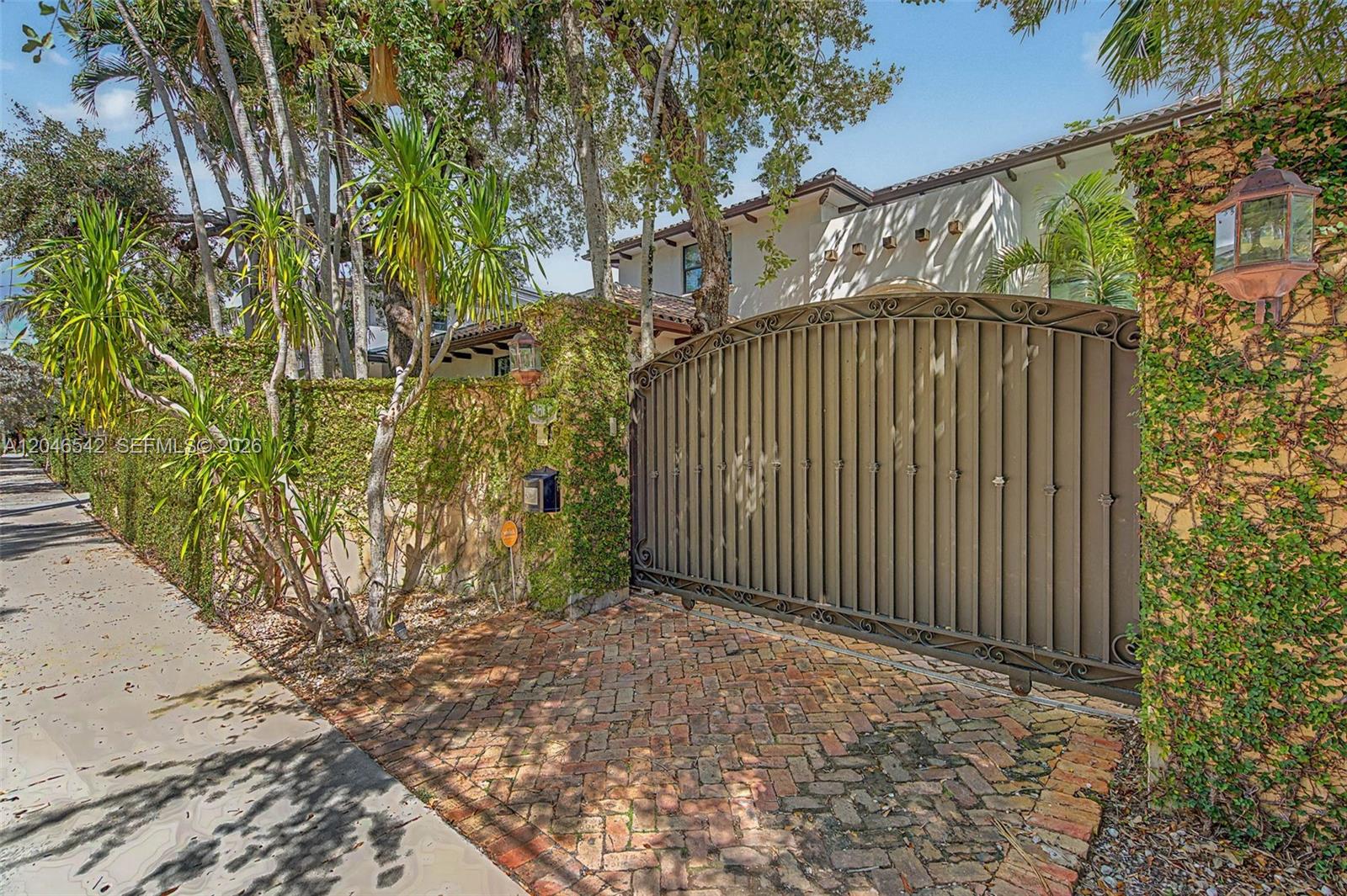 A large metal gate stands at the entrance of a house with ivy-covered walls — 2561 Trapp Ave, Miami FL 33133, MIAMI, FL