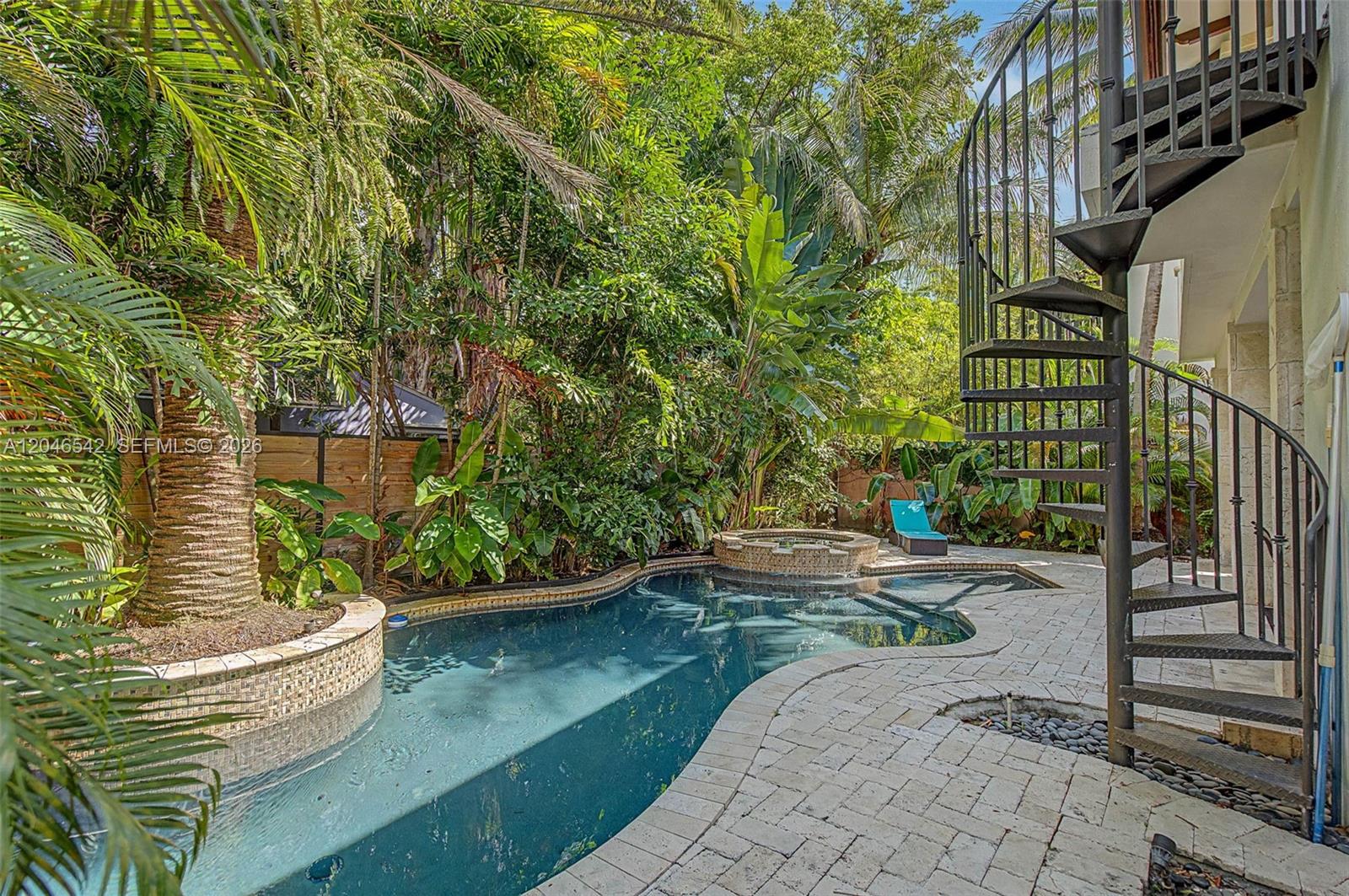 A backyard features a curved swimming pool, a small hot tub, and a spiral staircase — 2561 Trapp Ave, Miami FL 33133, MIAMI, FL