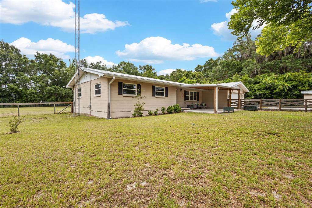 A tan, single-story house with a metal roof and a covered patio in a yard — 7251 NW 40TH STREET, CHIEFLAND, FL
