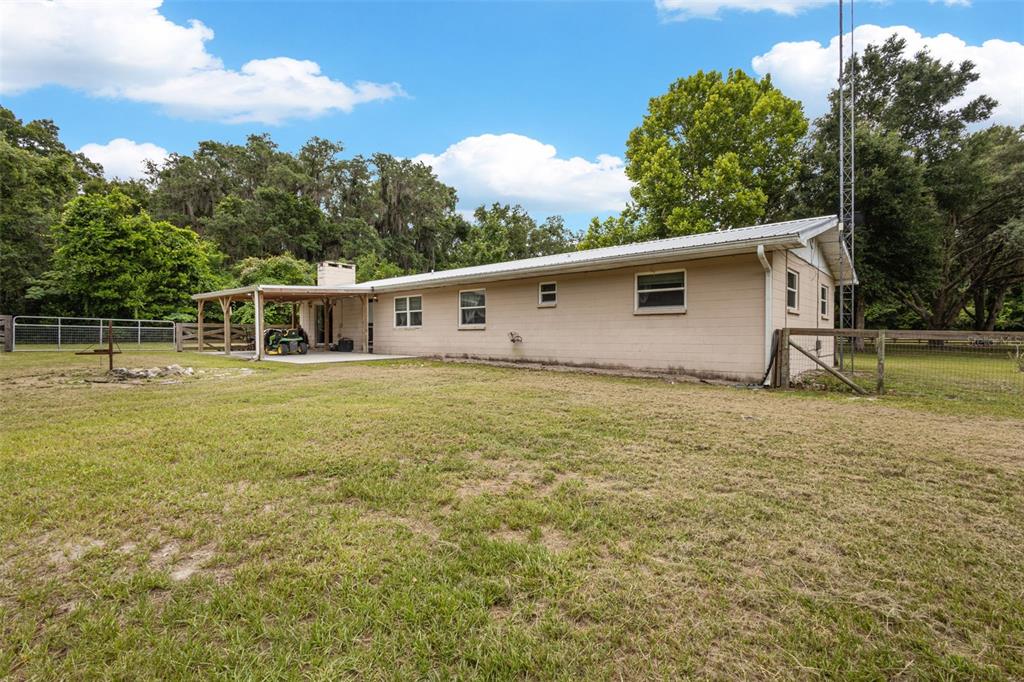 A single-story house with a metal roof and a covered patio sits on a grassy lot — 7251 NW 40TH STREET, CHIEFLAND, FL
