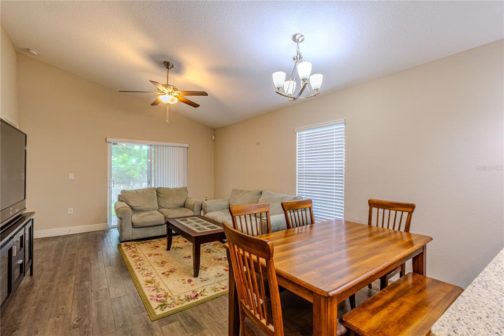 A living and dining area features wood-look flooring, a ceiling fan, and a chandelier — 8593 PLUMERIA AVENUE, ORLANDO, FL
