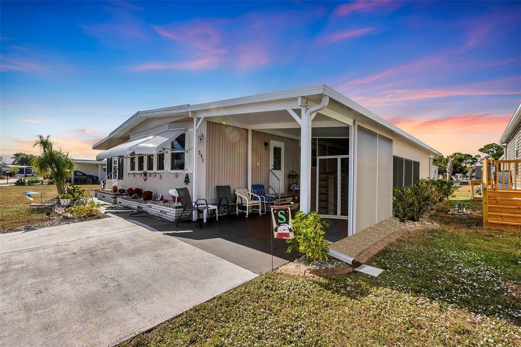 A single-story manufactured home features a covered carport, a concrete driveway, and a small porch — 220 LA ROSAS, NORTH PORT, FL
