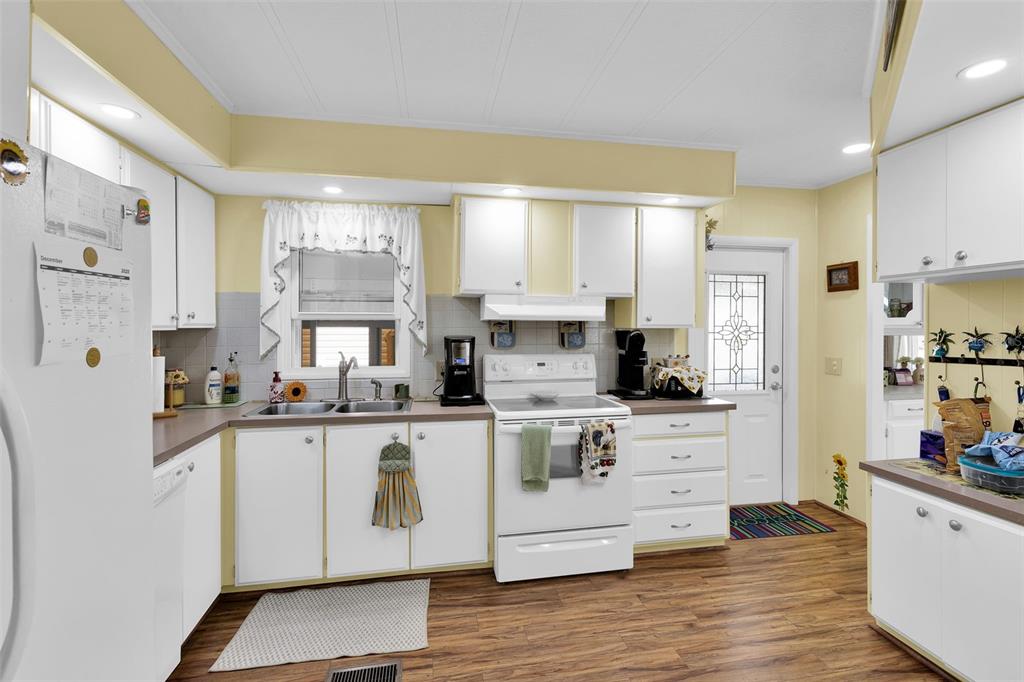 A kitchen with white cabinets, a white stove, a double sink, and wood-look flooring — 220 LA ROSAS, NORTH PORT, FL