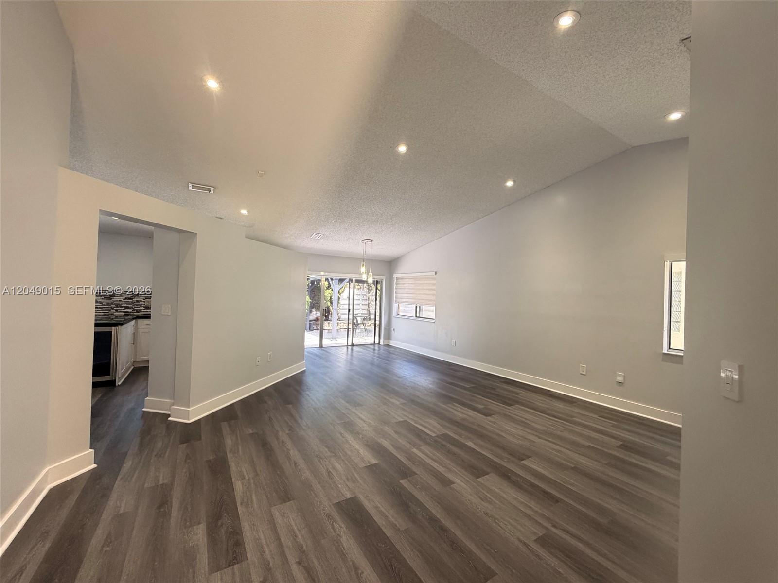 A spacious living room features vaulted ceilings, recessed lighting, and dark wood-look flooring — 14467 SW 137th Ct, Miami FL 33186, MIAMI, FL