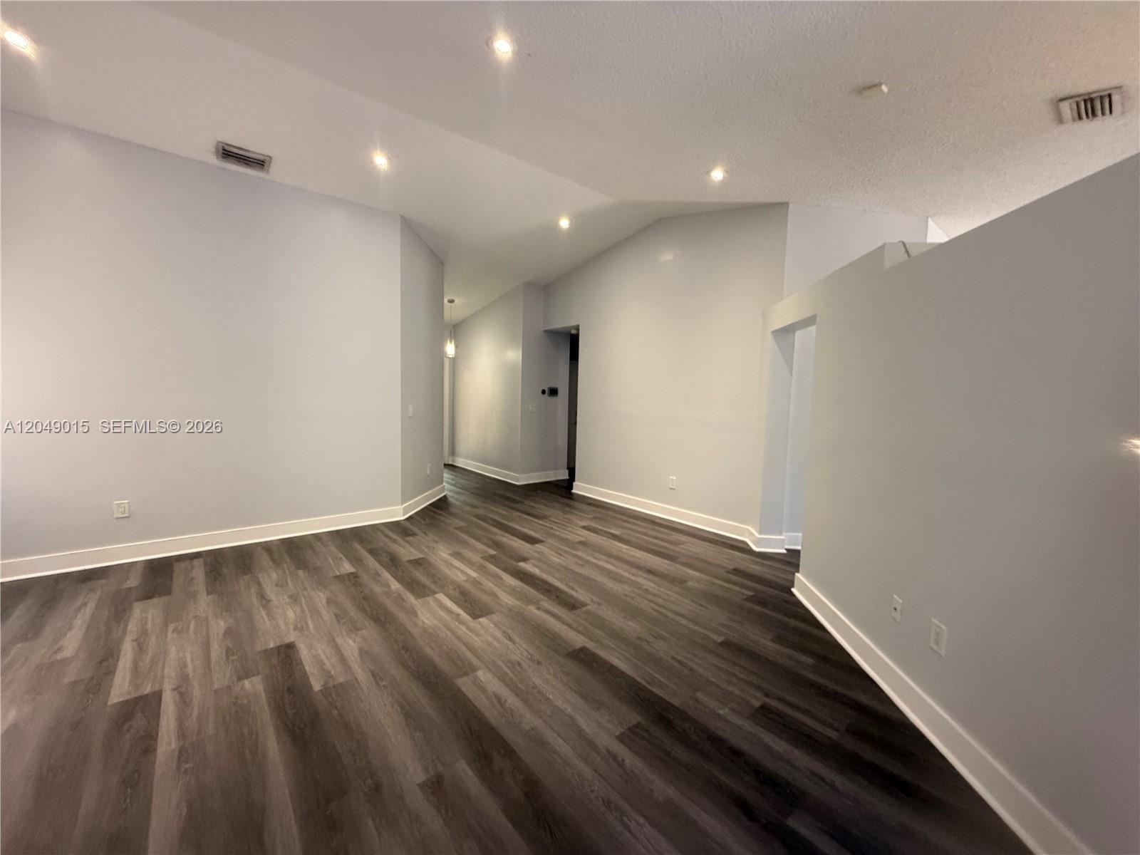 An empty room features light gray walls, white trim, and dark wood-look flooring — 14467 SW 137th Ct, Miami FL 33186, MIAMI, FL