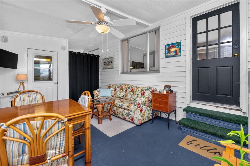 A sunroom features a floral sofa, dining set, ceiling fan, and a dark exterior door — 6741 LAUREL COURT, NORTH PORT, FL