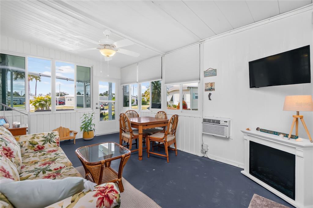 A sunroom features a floral sofa, dining set, wall-mounted television, and a fireplace — 6741 LAUREL COURT, NORTH PORT, FL