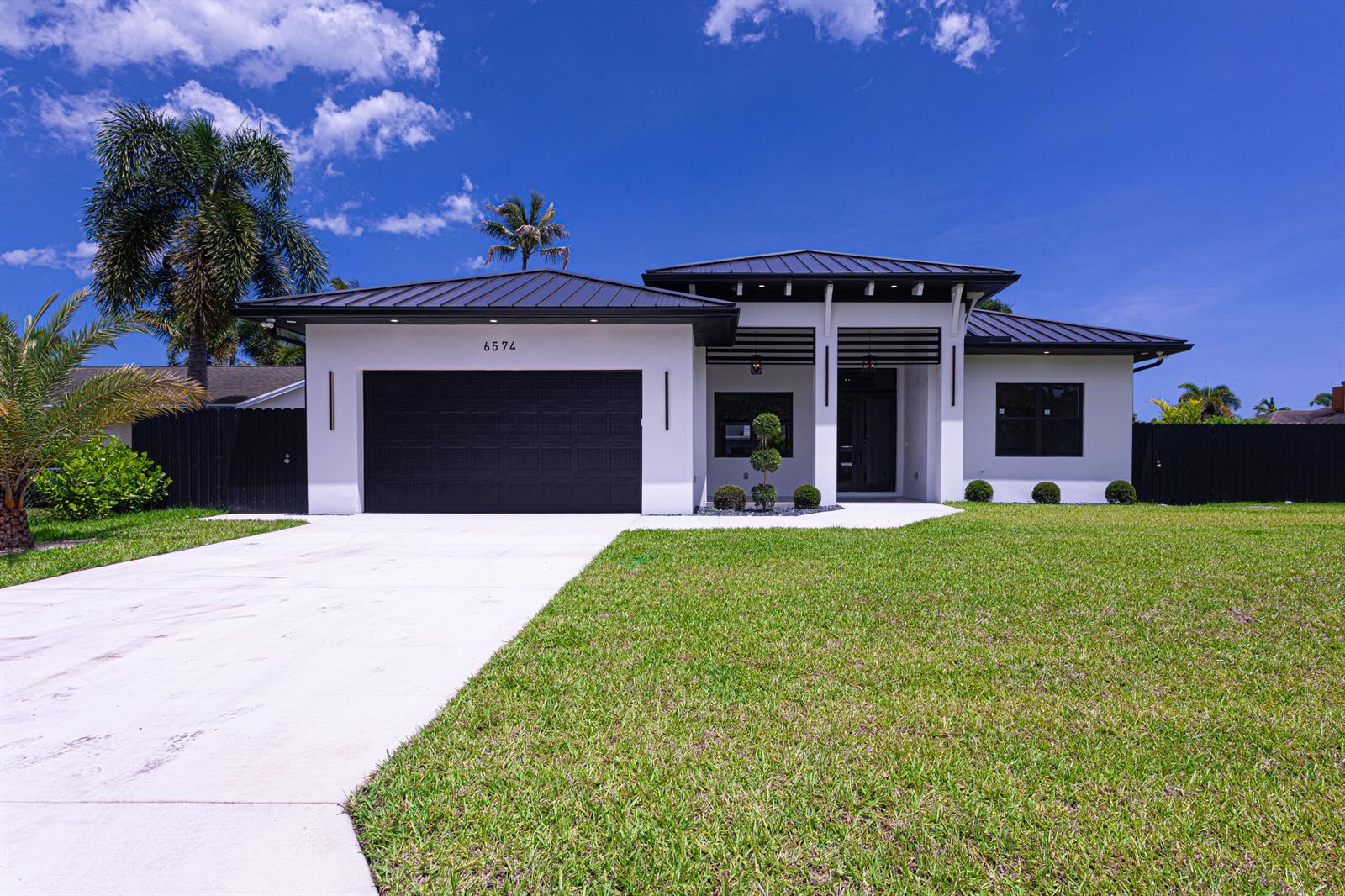 A modern single-story house features a black metal roof, white stucco walls, and a garage — 6574 Rigger Road, Lake Worth FL 33462, LAKE WORTH, FL