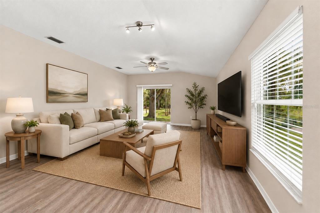 A living room features a beige sofa, wooden coffee table, armchair, and large windows — 5852 AUTUMN SHIRE, ZEPHYRHILLS, FL