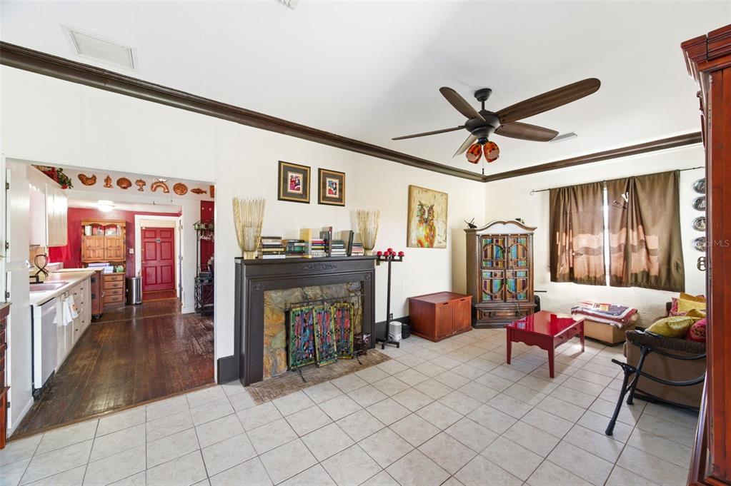 A living room with tile flooring, a fireplace, a ceiling fan, and an adjacent kitchen — 4263 5TH AVENUE N, ST PETERSBURG, FL