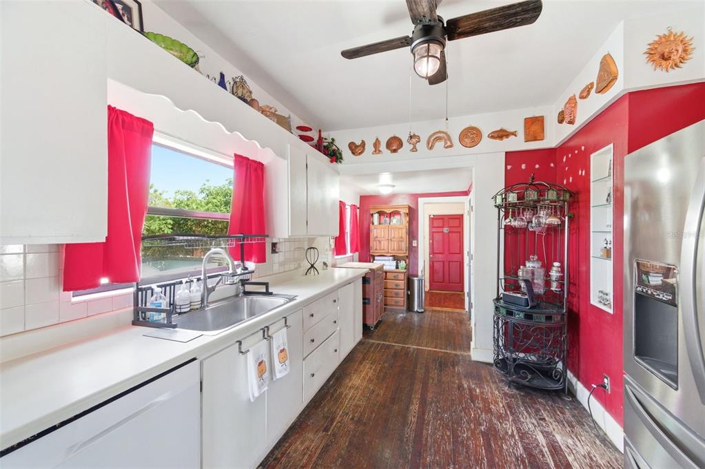 A kitchen features white cabinets, a stainless steel sink, red walls, and dark wood flooring — 4263 5TH AVENUE N, ST PETERSBURG, FL