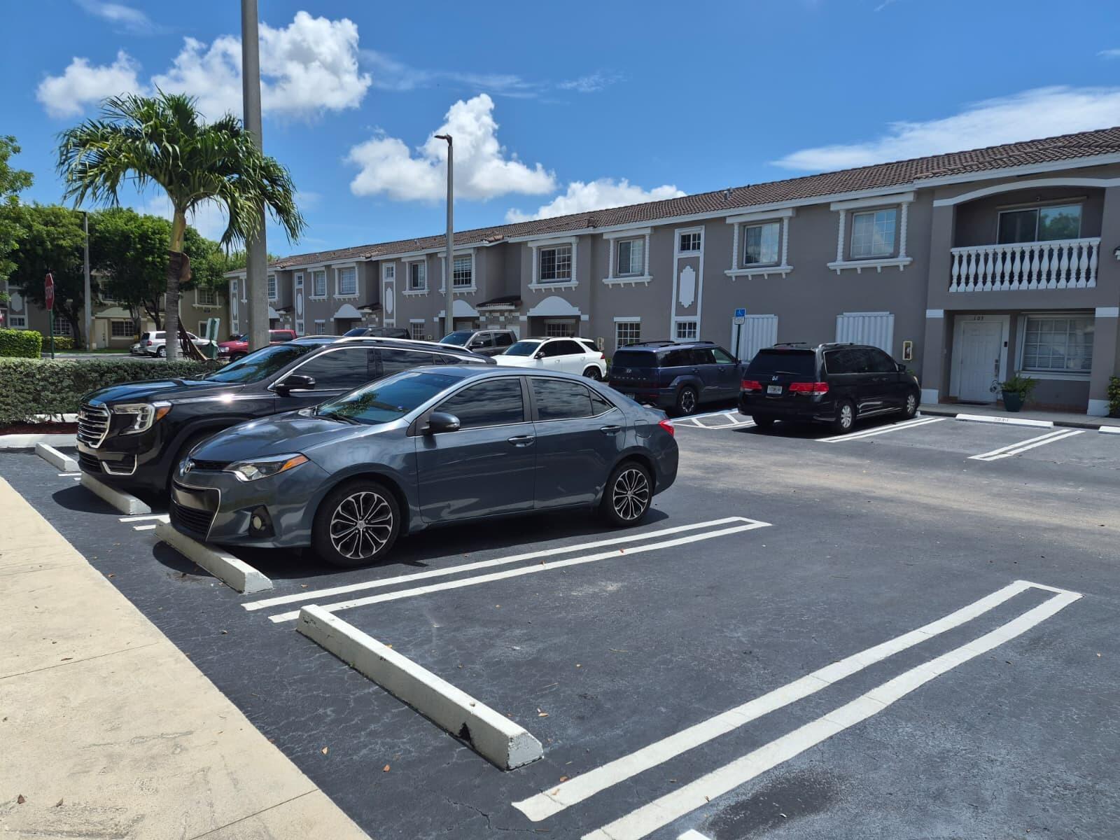 A multi-story residential building with a parking lot in the foreground under a blue sky — 7211 NW 174th Terrace # 203, Hialeah FL 33015, HIALEAH, FL