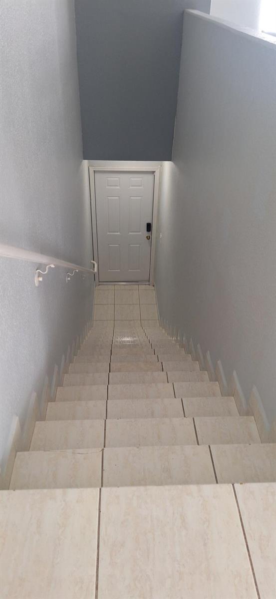 A staircase with light-colored tile steps leads down to a white door — 7211 NW 174th Terrace # 203, Hialeah FL 33015, HIALEAH, FL