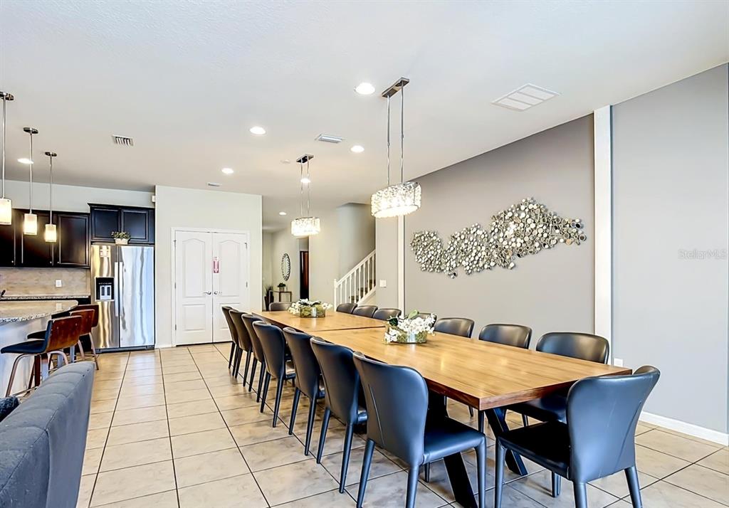 A long wooden dining table with black chairs sits in a room with tile floors — 1603 LIMA AVENUE, KISSIMMEE, FL