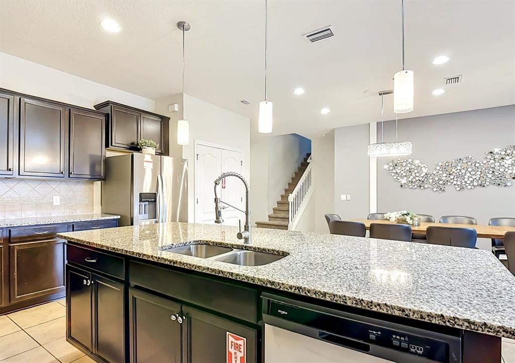 A kitchen features dark cabinets, granite countertops, a central island with a sink, and pendant lighting — 1603 LIMA AVENUE, KISSIMMEE, FL