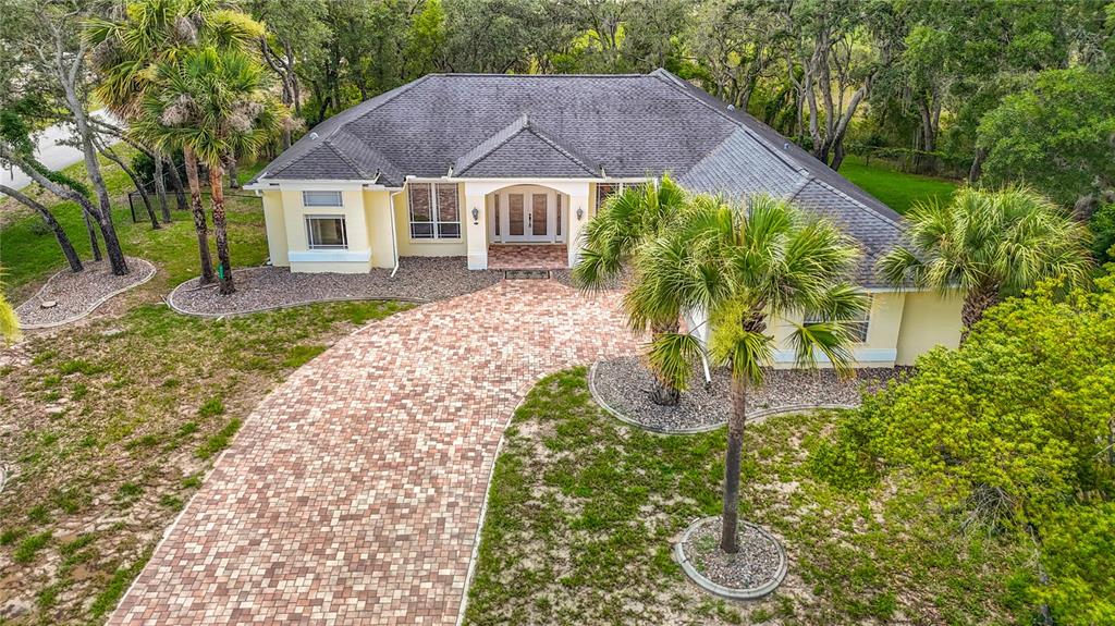 An aerial view of a single-story house with a paver driveway and palm trees — 9433 WILDERNESS TRAIL, WEEKI WACHEE, FL