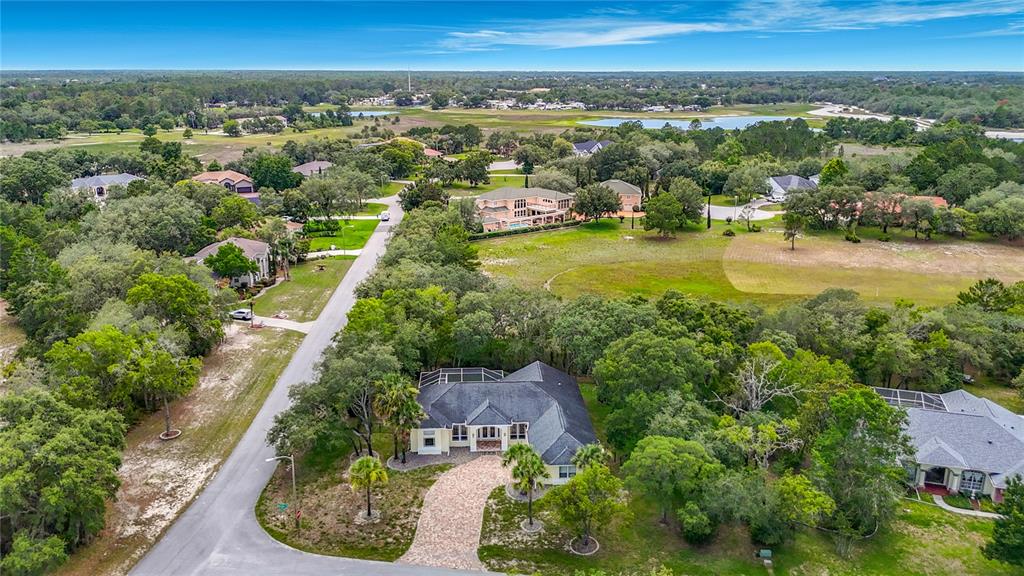 An aerial view shows a suburban house with a paved driveway surrounded by trees — 9433 WILDERNESS TRAIL, WEEKI WACHEE, FL