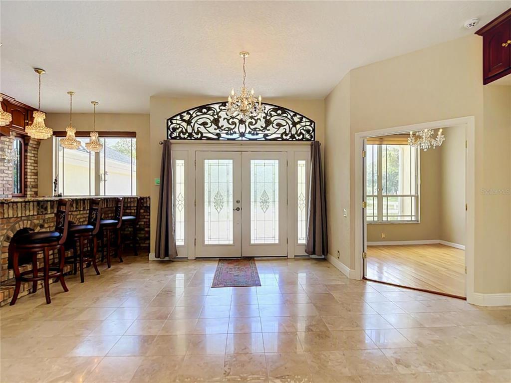 A tiled entryway features double glass doors with an ornate metal arch and a chandelier — 9433 WILDERNESS TRAIL, WEEKI WACHEE, FL