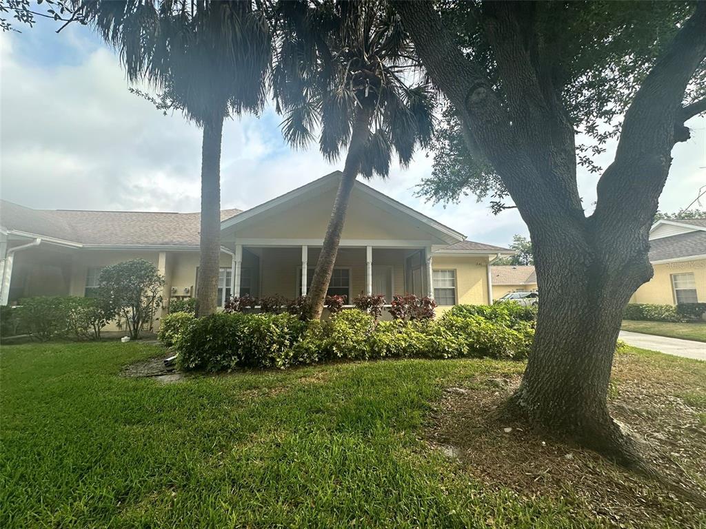 A yellow one-story house with a covered front porch, palm trees, and a large oak tree — 1641 RED OAK LANE, PORT CHARLOTTE, FL