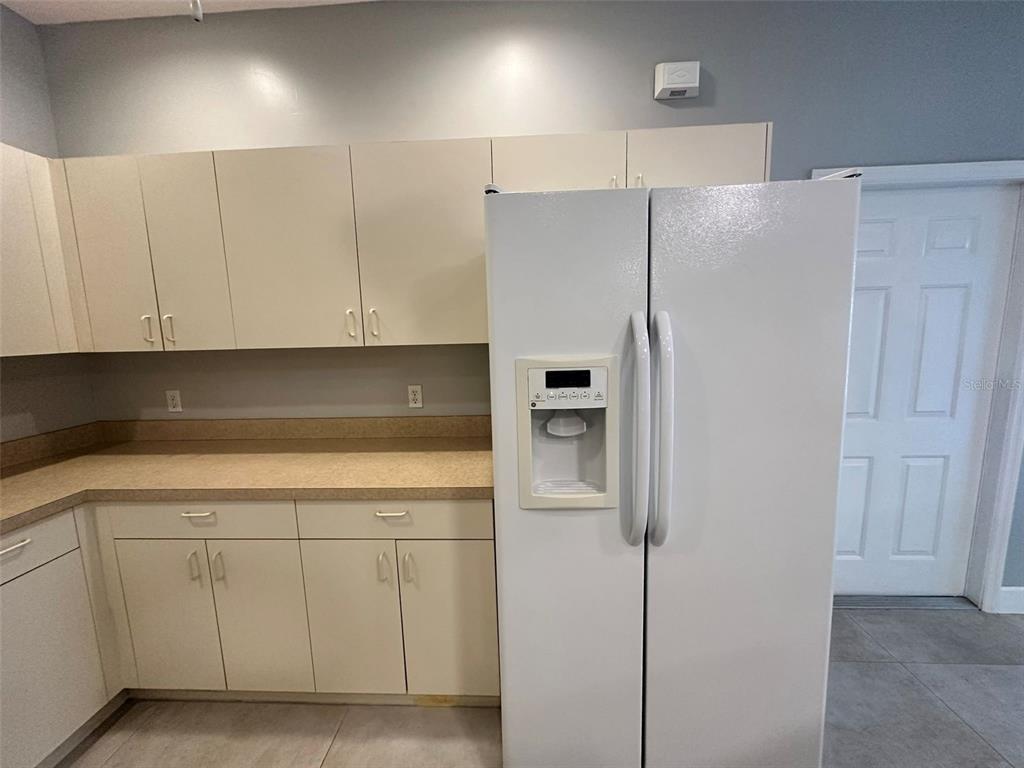 A kitchen features beige cabinets, a tan laminate countertop, and a white side-by-side refrigerator — 1641 RED OAK LANE, PORT CHARLOTTE, FL