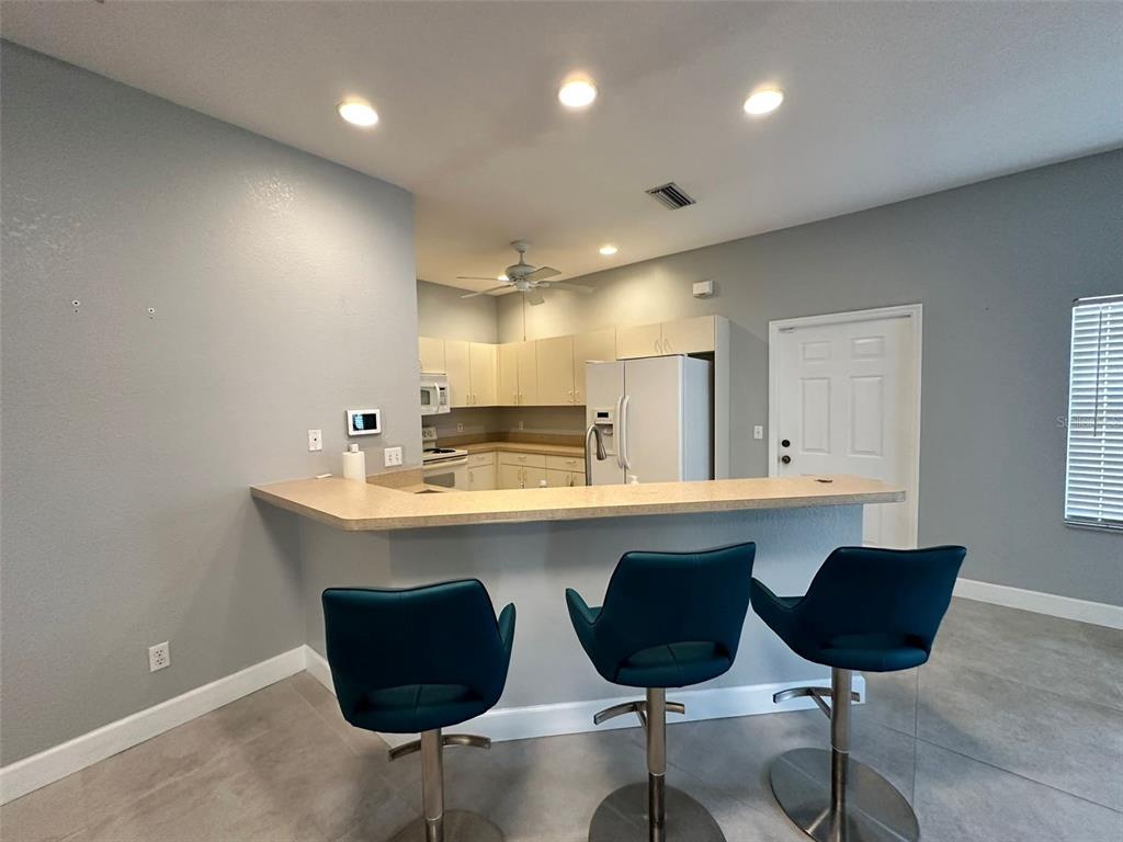A kitchen with light cabinets and a breakfast bar featuring three teal bar stools — 1641 RED OAK LANE, PORT CHARLOTTE, FL