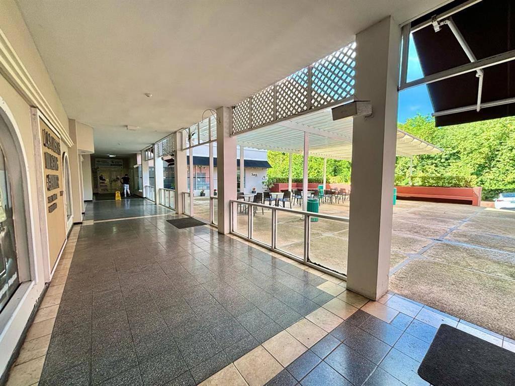 A covered outdoor walkway with tiled flooring leads to an open-air patio area with tables — 300 AVENIDA LAS CUMBRES, SAN JUAN, PR