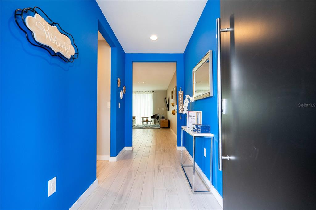 A bright blue entryway features light wood-look tile flooring and a modern console table — 4439 LE REVE COURT, KISSIMMEE, FL