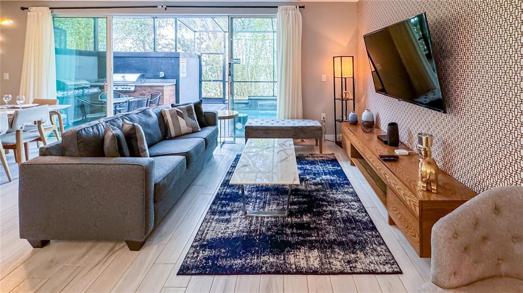 A living room features a gray sofa, a blue area rug, and a wall-mounted television — 4439 LE REVE COURT, KISSIMMEE, FL