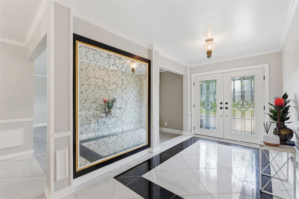 A bright entryway features white and black tiled floors, a large decorative mirror, and double doors — 3678 E LAKE DRIVE, LAND O LAKES, FL