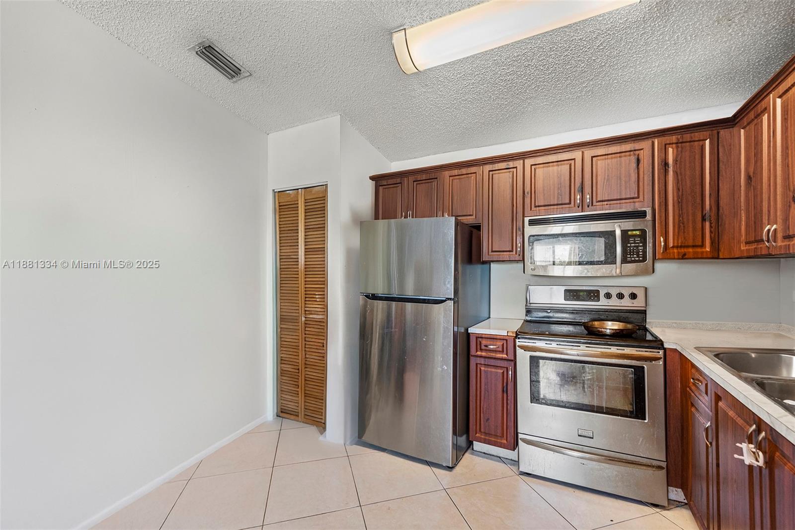 A kitchen features wood cabinets, stainless steel appliances, and light-colored tile flooring — 3630 N 56th Ave # 323, Hollywood FL 33021, HOLLYWOOD, FL