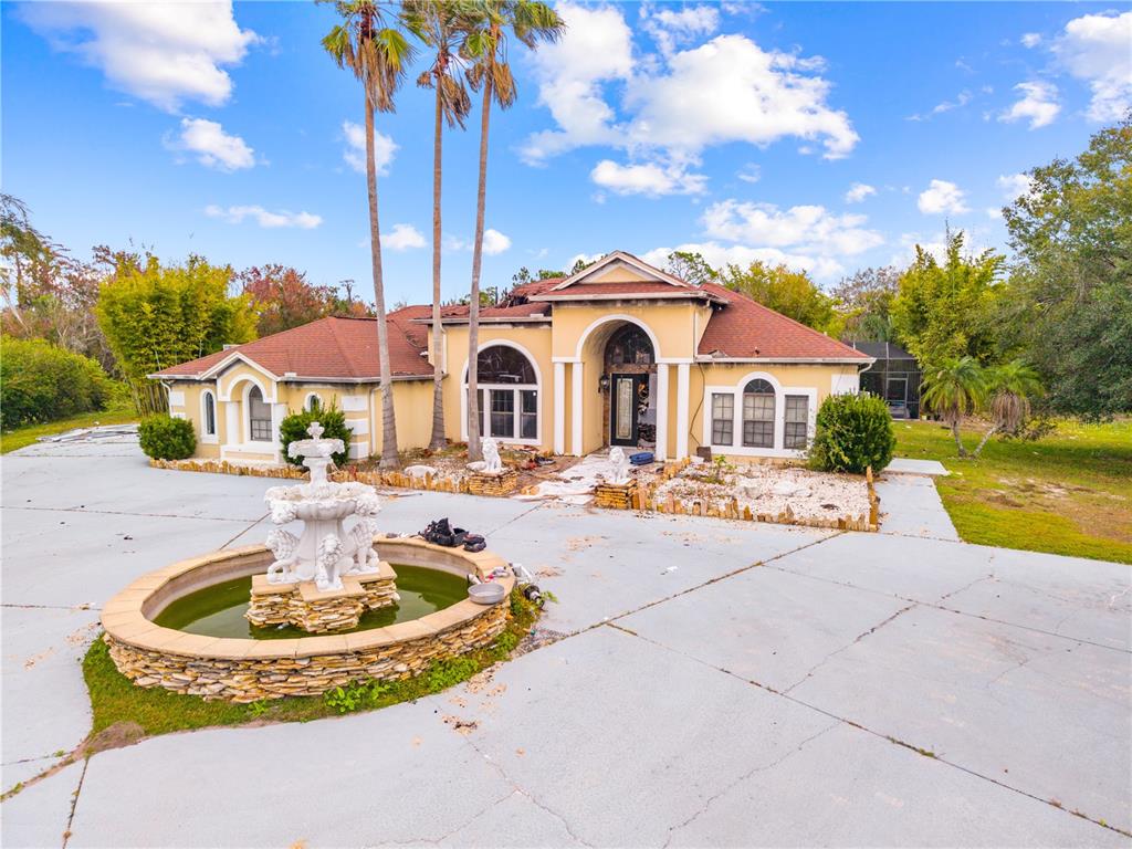 A single-story house with a fountain in the driveway and visible fire damage — 214 TARANTO WAY, KISSIMMEE, FL