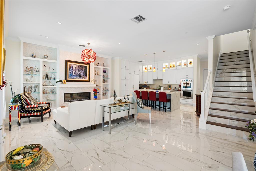 A bright open-concept living room and kitchen featuring white marble floors and a grand staircase — 1 PALM TERRACE, BELLEAIR, FL