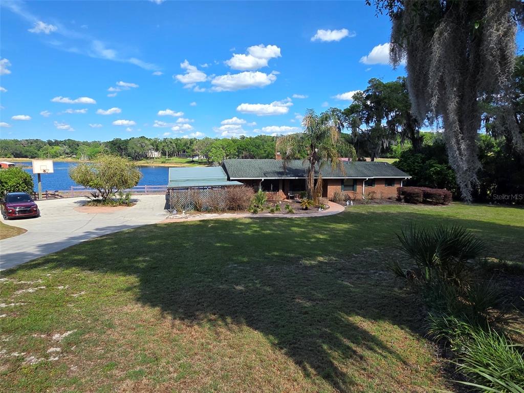 A single-story brick house sits on a grassy lot next to a lake — 2285 WILMHURST ROAD, DELAND, FL