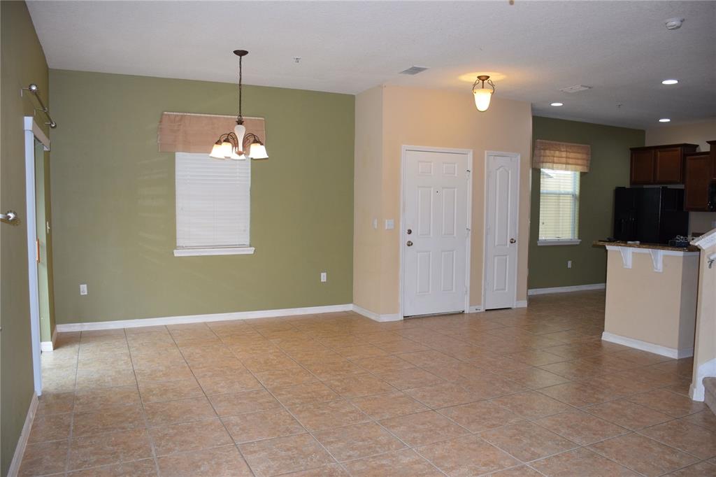 An open-concept living area features olive green walls, tile flooring, and a dining light fixture — 1516 SCARLET OAK LOOP UNIT B, WINTER GARDEN, FL
