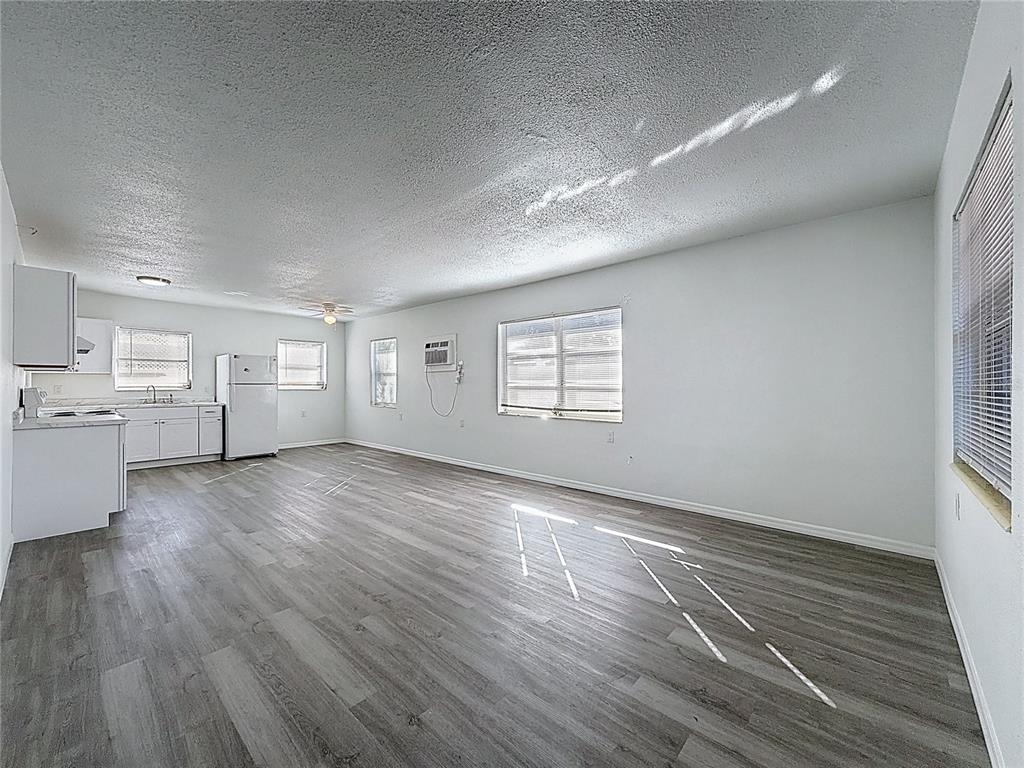 A bright, open-concept kitchen and living area featuring white cabinets and gray wood-look flooring — 650 E HARBOR DRIVE S, ST PETERSBURG, FL