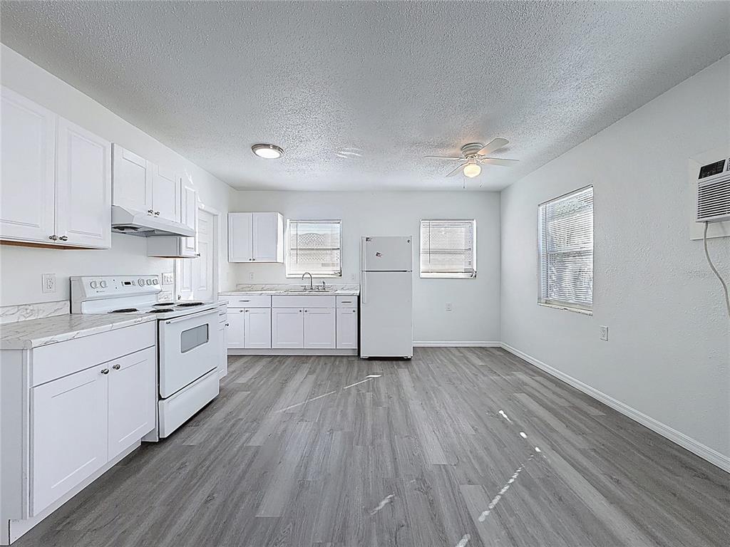 A kitchen with white cabinets, white appliances, and gray wood-look flooring — 650 E HARBOR DRIVE S, ST PETERSBURG, FL
