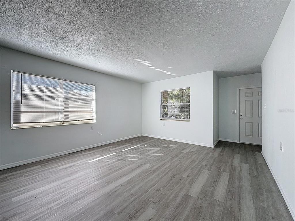 An empty room with light gray walls, wood-look flooring, two windows, and a white door — 650 E HARBOR DRIVE S, ST PETERSBURG, FL