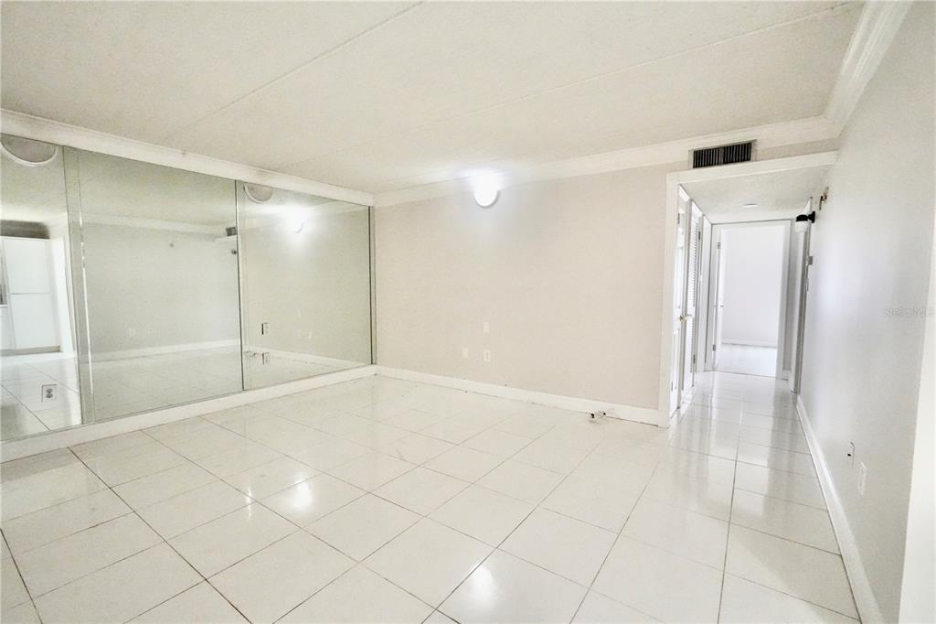 An empty room with white tile floors, a mirrored wall, and a hallway entrance — 4718 CHRISTA COURT UNIT 317, TAMPA, FL