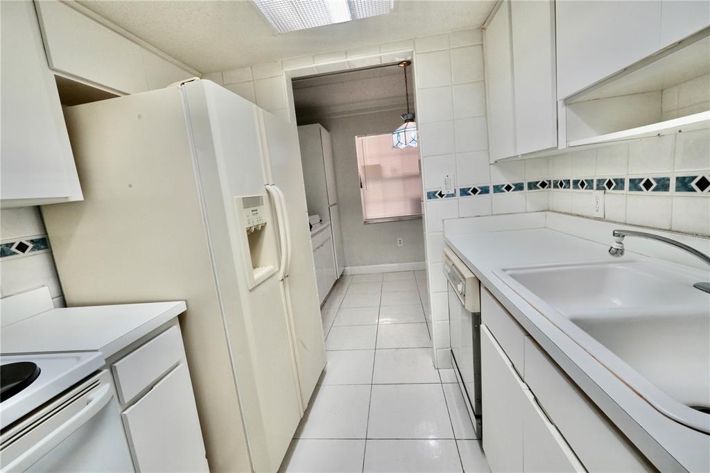 A kitchen with white cabinets, white appliances, tiled floors, and a tiled backsplash — 4718 CHRISTA COURT UNIT 317, TAMPA, FL